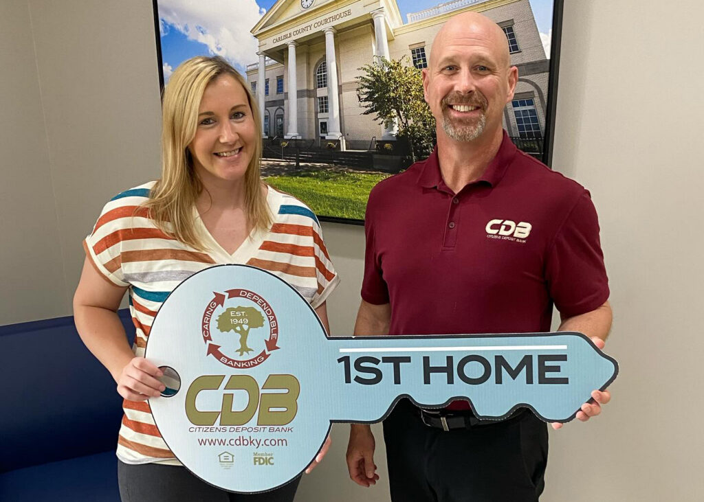 CDB Customer holding large key that says "1st Home" next to a CDB employee
